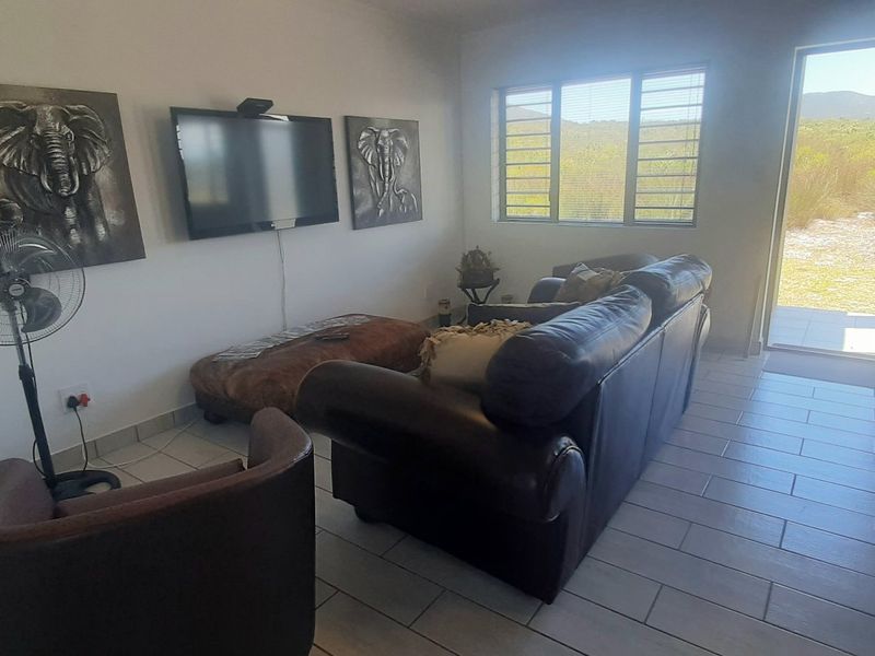 A living room featuring tiled flooring, aluminium window frames with security bars, and a glass sliding door providing access to the exterior.