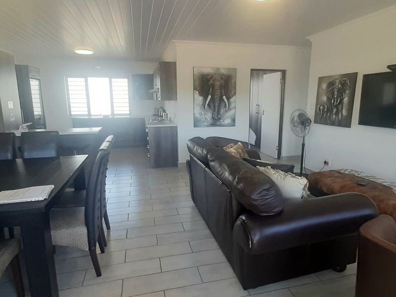 Open-plan living and dining area featuring tiled flooring, a tongue and groove ceiling, and an integrated kitchen space.