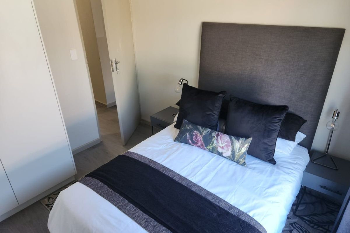 A well-maintained bedroom featuring neutral walls, laminate flooring, and a built-in wardrobe, offering a clean and functional living space.