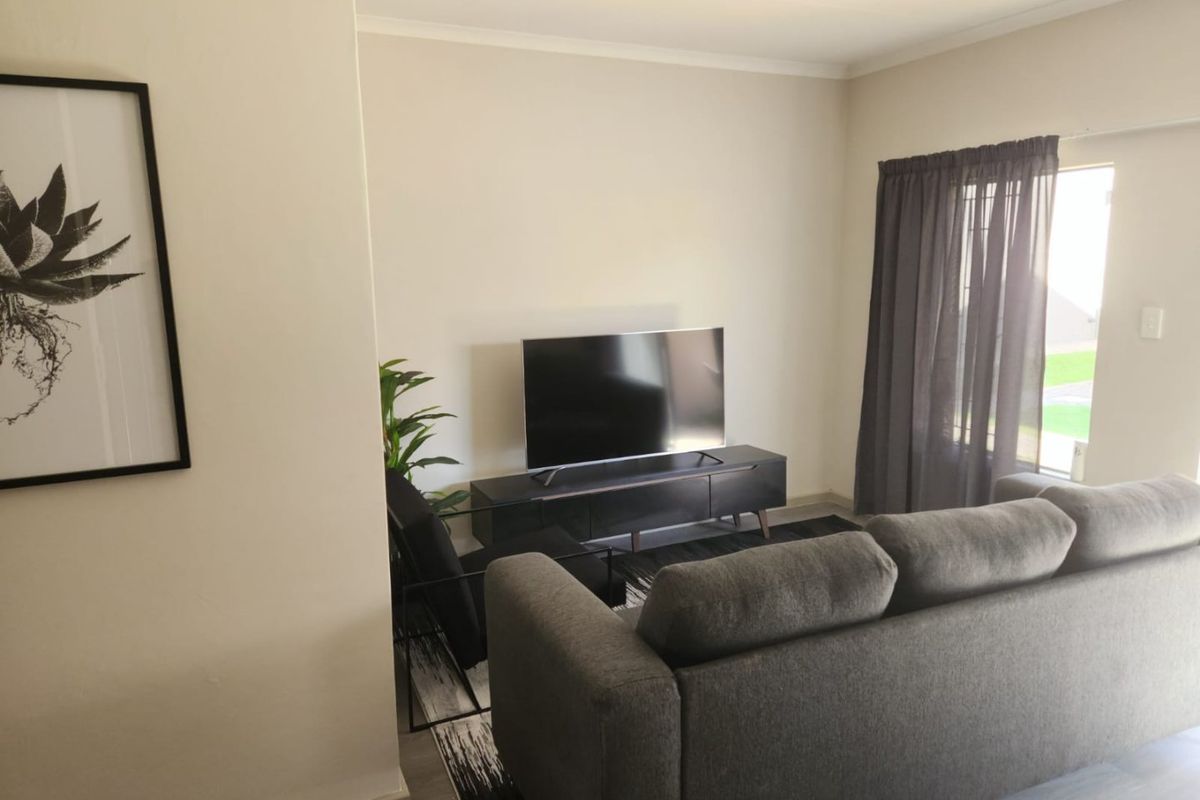 A well-maintained living room featuring neutral wall tones, natural light through a glass door, and modern finishes.