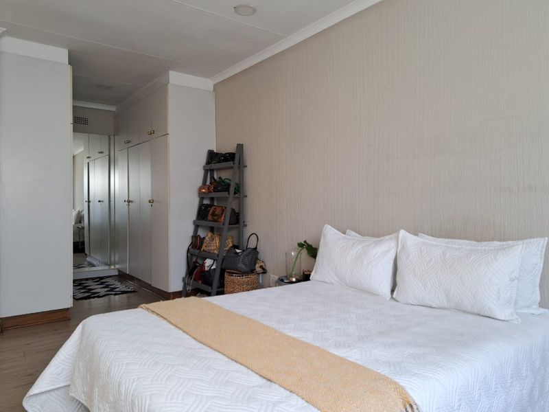 A well-maintained bedroom featuring built-in cupboards with mirrored doors, recessed lighting, and neutral wall finishes.