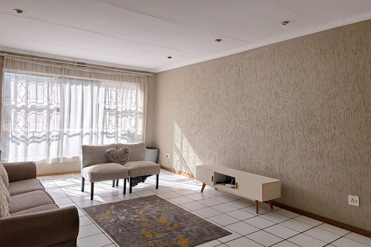 A bright living room featuring tiled flooring, textured feature wall, and recessed downlights, offering a neutral canvas for interior design updates.