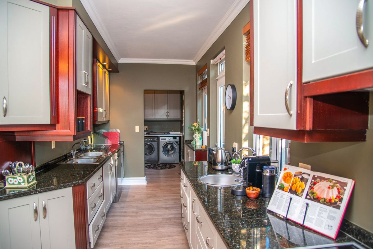 A well-maintained kitchen featuring granite countertops, ample built-in cabinetry, and a functional layout with an adjacent laundry area.