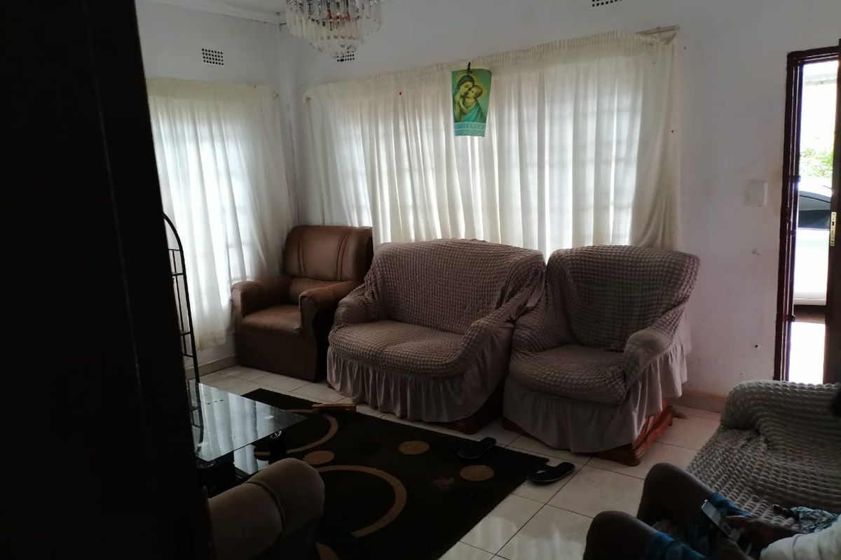A living room featuring tiled flooring and a central chandelier, requiring cosmetic updates to improve the overall aesthetic and condition of the space.