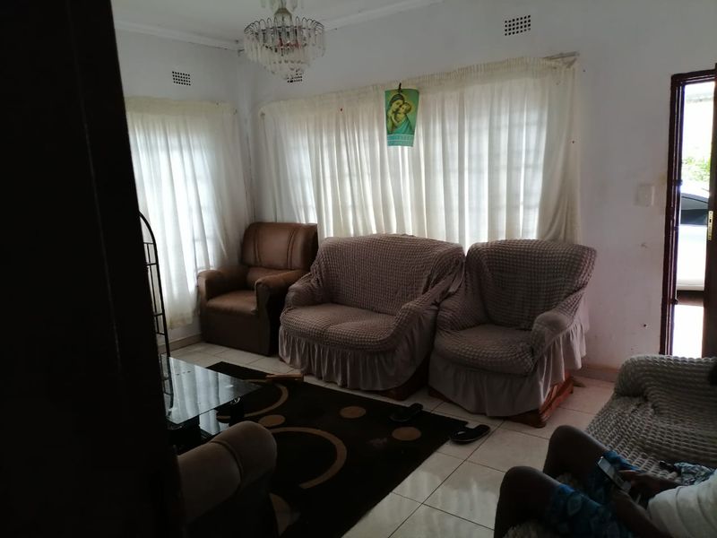 A living room featuring tiled flooring and a central chandelier, requiring cosmetic updates to improve the overall aesthetic and condition of the space.
