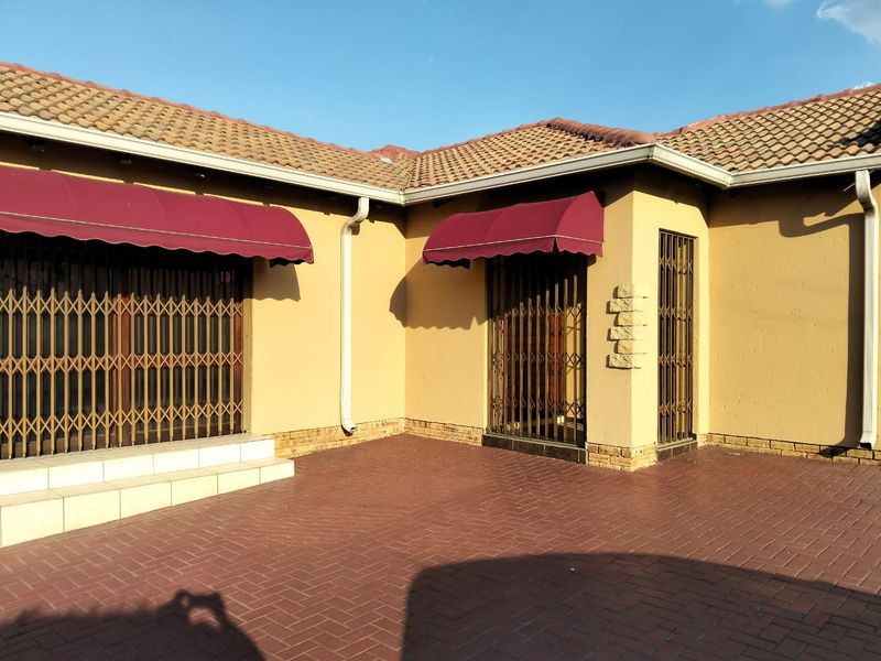 Rear exterior view of the townhouse featuring brick paving, security gates, and protective awnings over the access points.