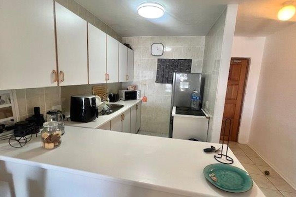 A functional kitchen featuring white cabinetry, tiled backsplash, and a breakfast bar, providing a practical layout for daily meal preparation.