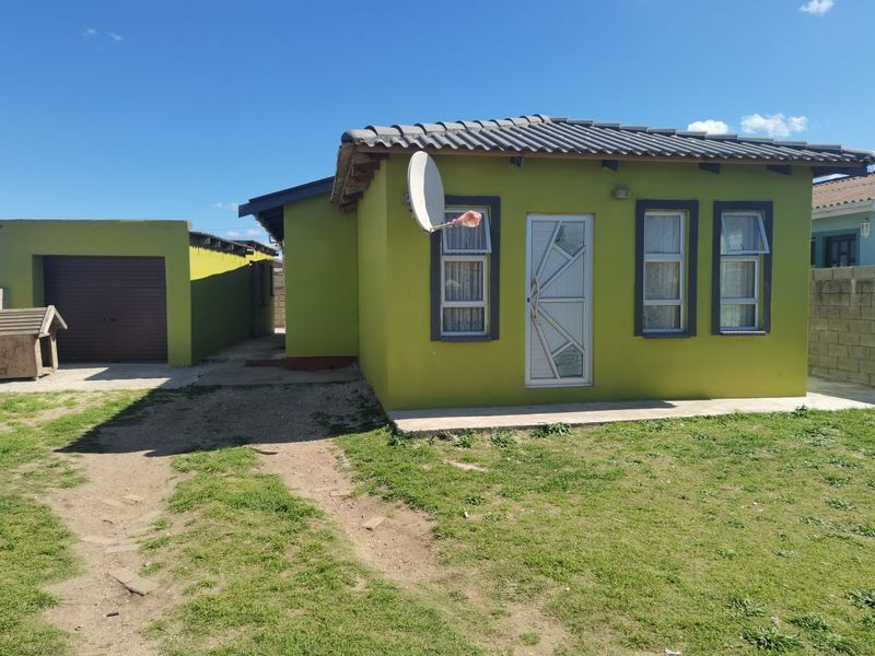 Front view of a detached house featuring a tiled roof, aluminium window frames, security gate, and an attached garage with a concrete driveway.