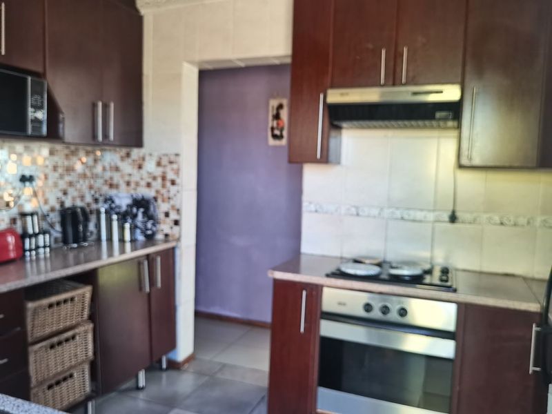 A functional kitchen featuring dark wood cabinetry, a built-in oven with hob, extractor fan, and tiled backsplash.