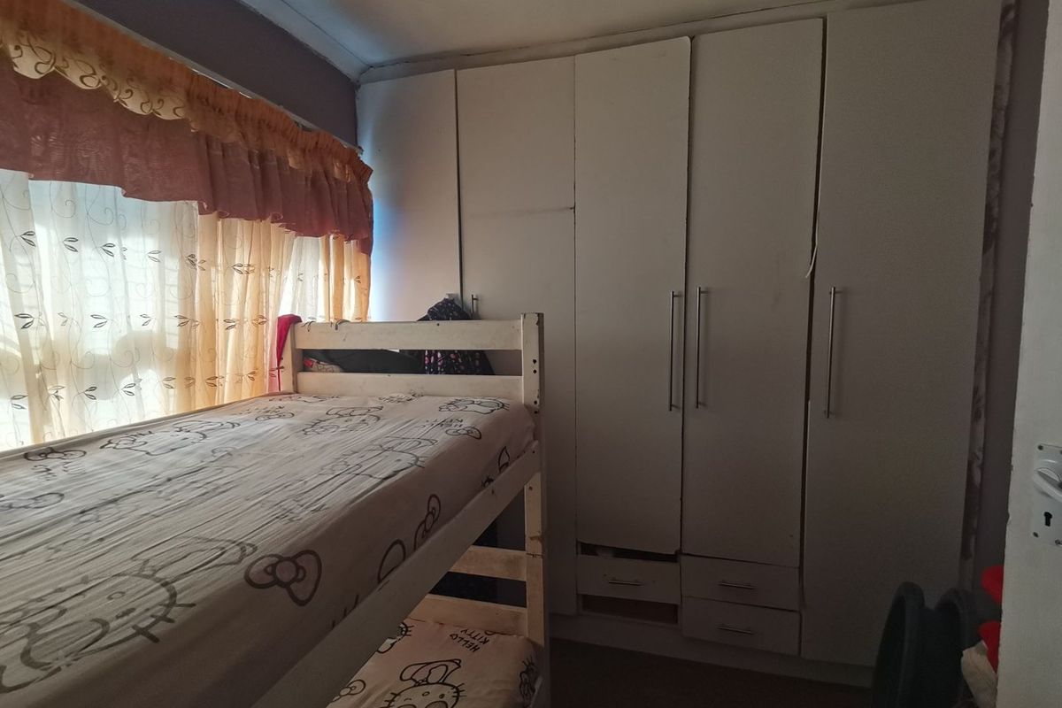 A bedroom featuring built-in white cupboards with some visible wear and missing drawer components.