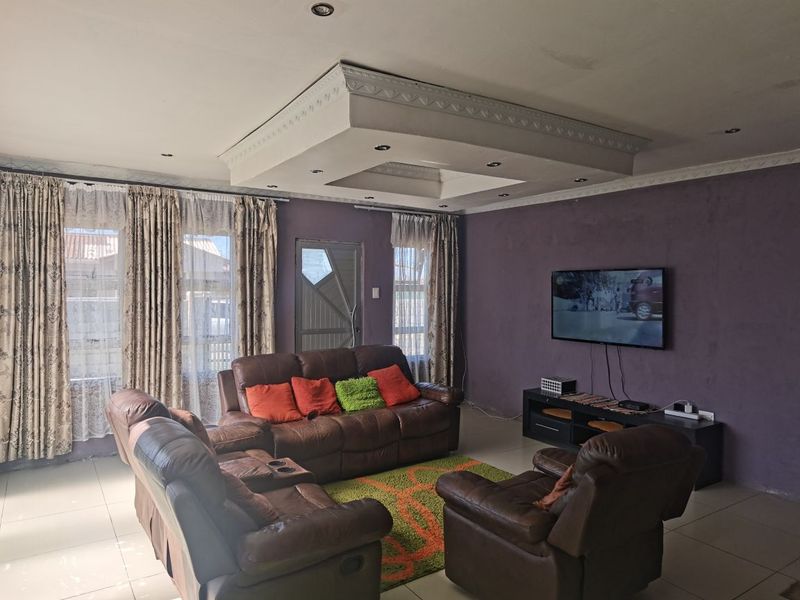 A living room featuring a decorative recessed ceiling with integrated lighting, tiled floors, and purple-toned walls.