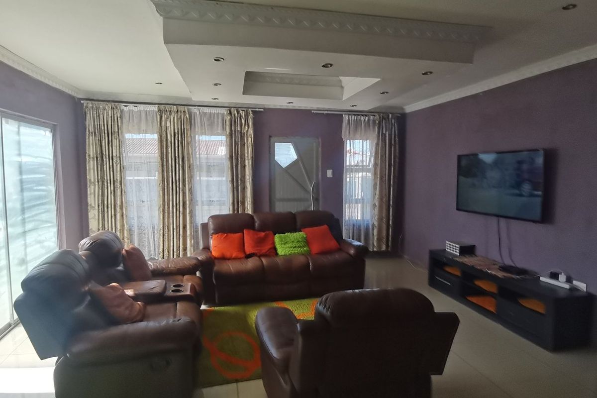 Spacious living room featuring a decorative recessed ceiling with integrated lighting, tiled flooring, and large sliding glass doors providing natural light.