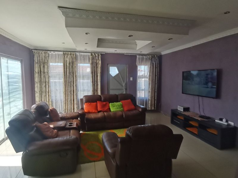 Spacious living room featuring a decorative recessed ceiling with integrated lighting, tiled flooring, and large sliding glass doors providing natural light.