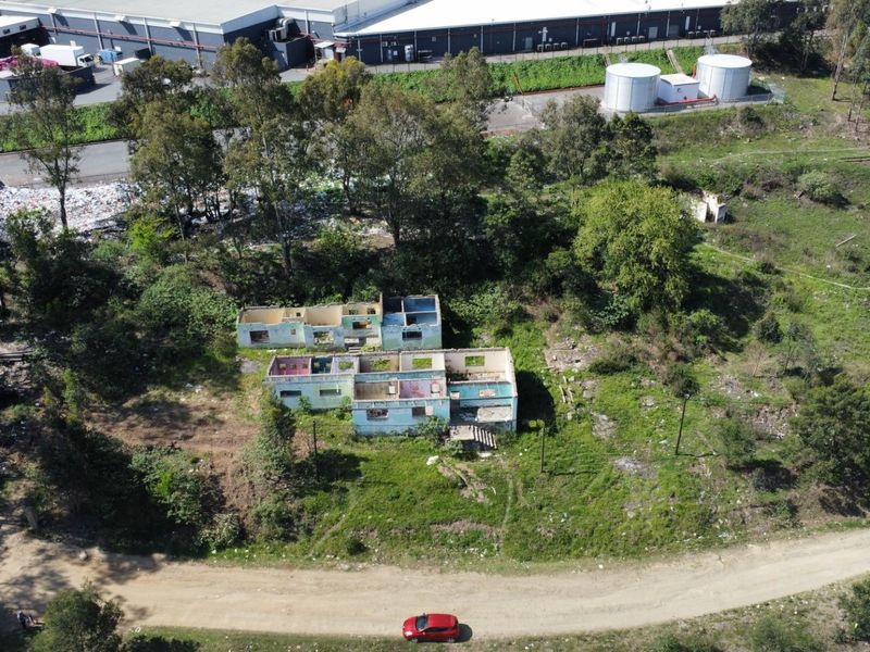Aerial view of a vacant residential plot featuring a dilapidated building shell in a state of severe disrepair.
