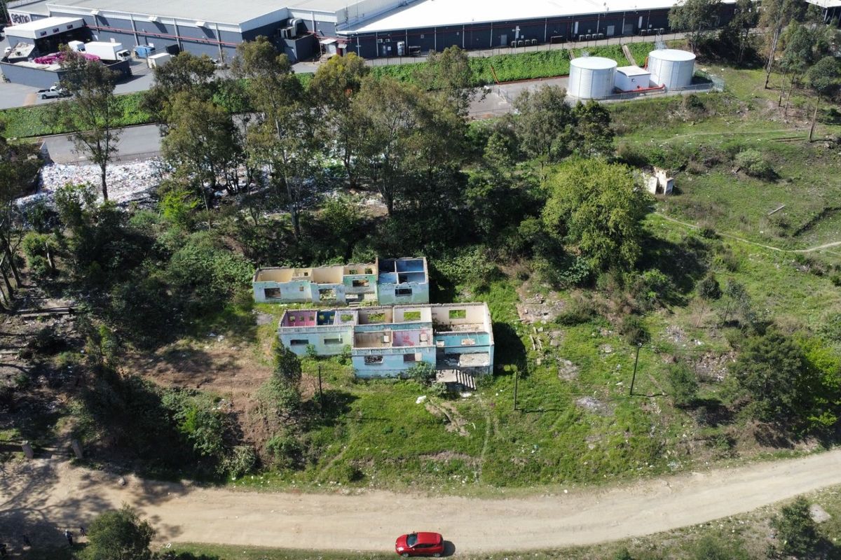 Aerial view of a vacant residential plot featuring a dilapidated building shell in a state of severe disrepair.