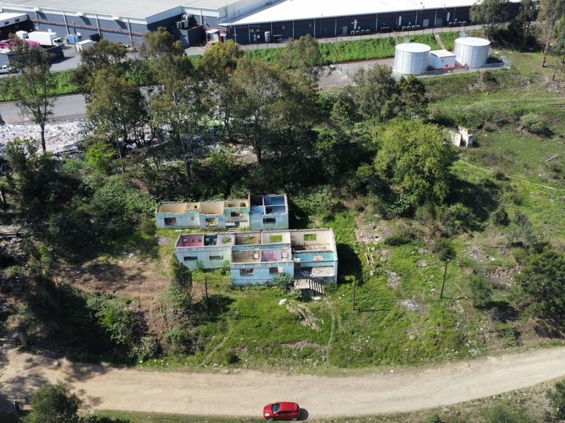 Aerial view of a vacant residential plot featuring a dilapidated building shell in a state of severe disrepair.