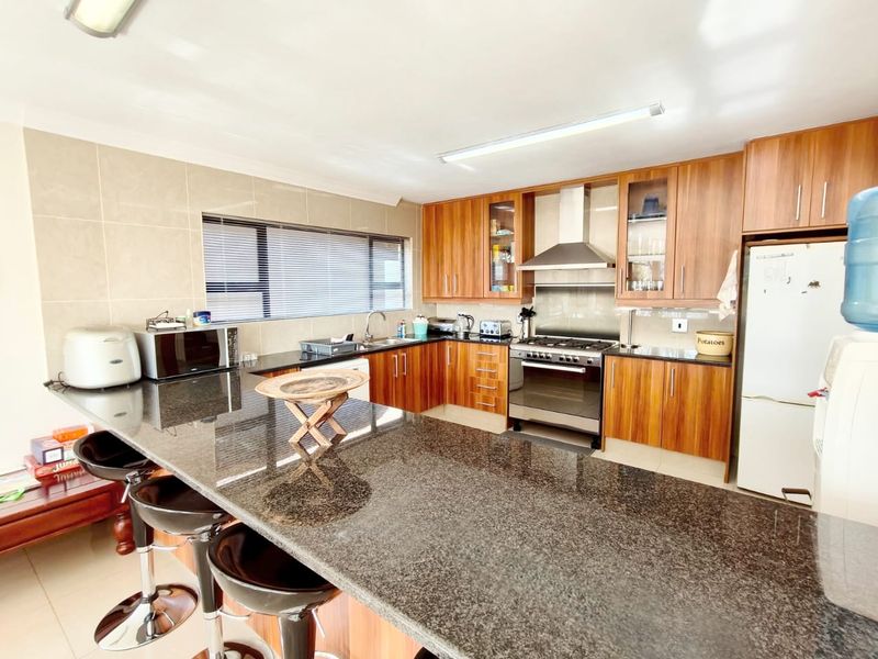 A well-maintained kitchen featuring granite countertops, wooden cabinetry, and stainless steel appliances, including a gas stove and extractor fan.