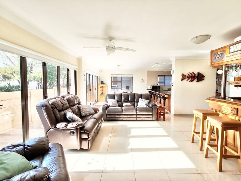 Spacious open-plan living area featuring tiled floors, a built-in bar, and large sliding glass doors that provide ample natural light and access to the exterior.