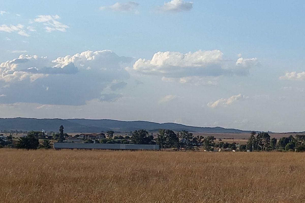 A wide-angle view of the vacant residential land featuring expansive grassy fields and distant mountain vistas under a clear sky.