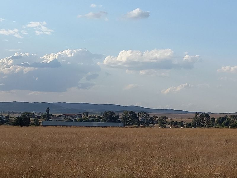 A wide-angle view of the vacant residential land, showcasing the expansive grassy terrain and distant landscape horizon.
