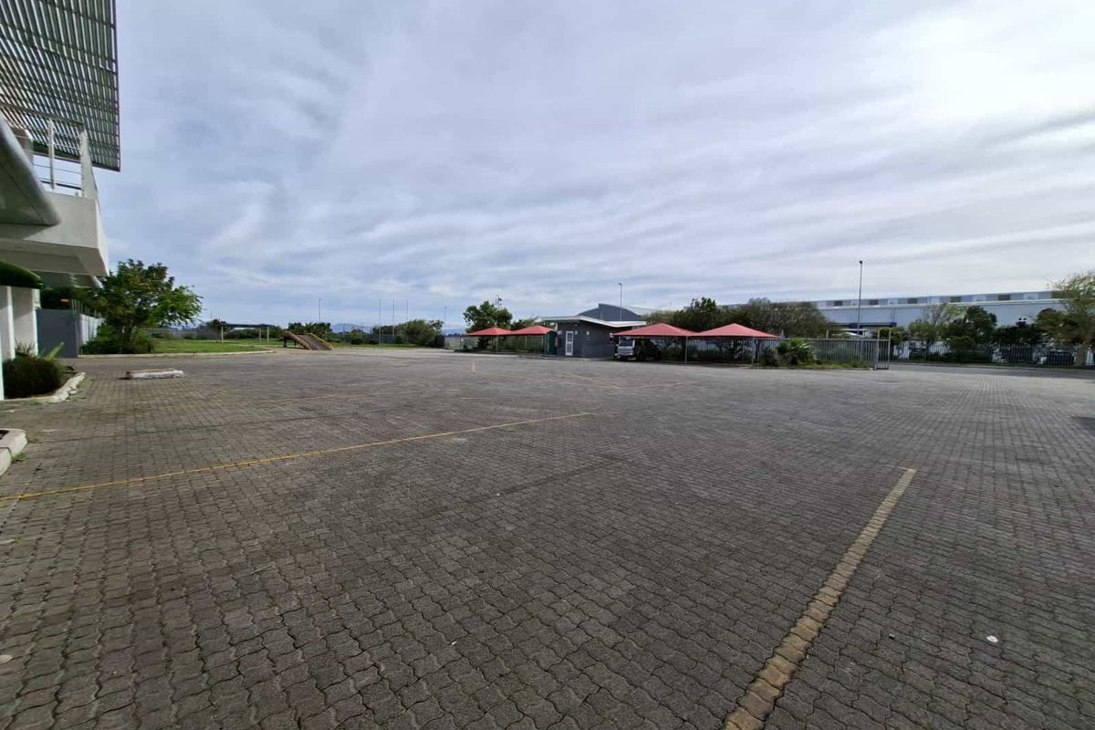 Expansive paved industrial parking area featuring multiple shade cloth carports and secure perimeter fencing.