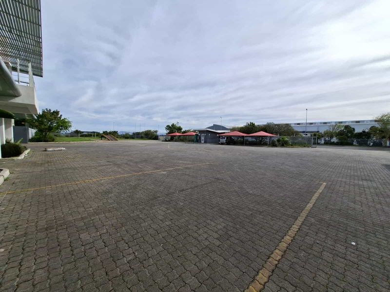Expansive paved industrial parking area featuring multiple shade cloth carports and secure perimeter fencing.
