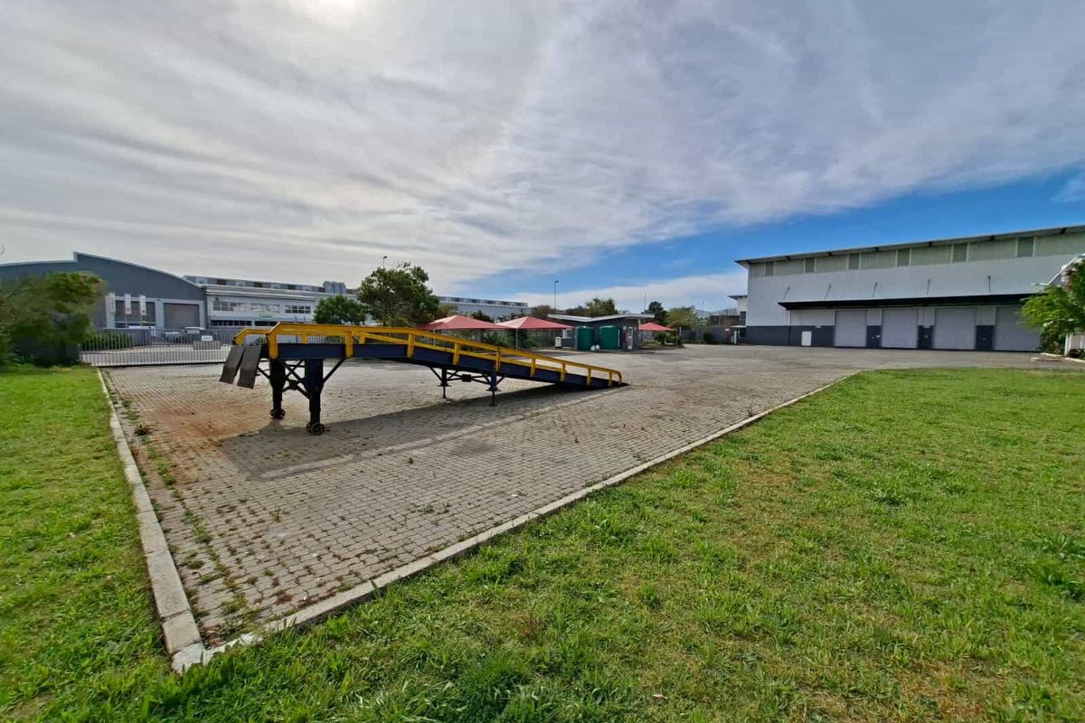 Spacious industrial yard featuring a paved surface, loading ramp, and access to a large warehouse facility.