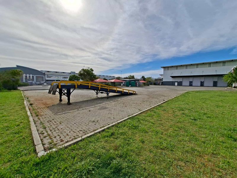 Spacious industrial yard featuring a paved surface, loading ramp, and access to a large warehouse facility.