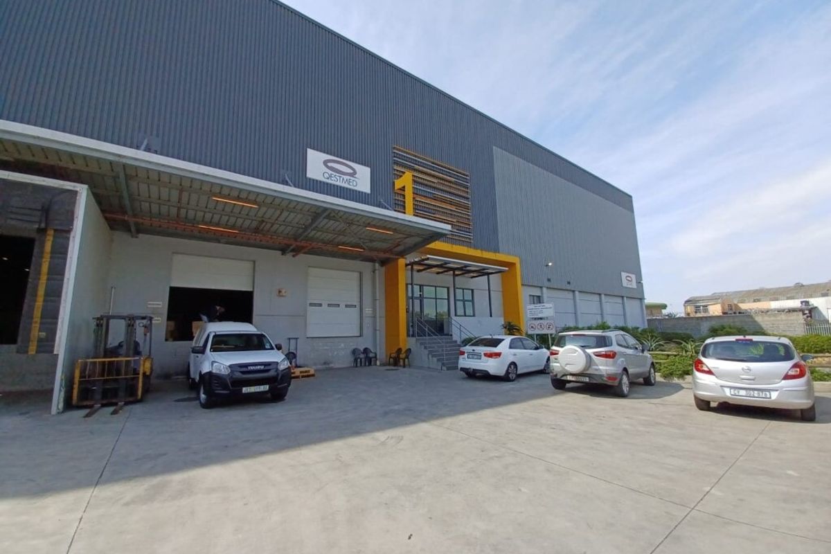 Industrial warehouse facility featuring a large corrugated metal facade, dedicated loading bay with roller shutter door, and a paved concrete yard area.