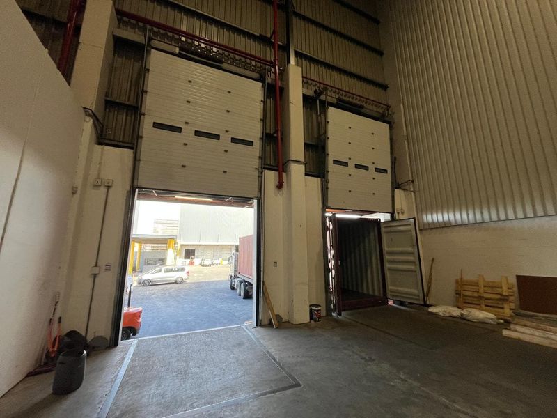 Industrial warehouse loading bay featuring high-clearance roller shutter doors, exposed structural steel, and durable concrete flooring suitable for logistics and storage operations.