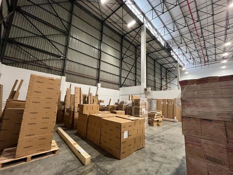 Spacious industrial warehouse area featuring high ceilings with exposed steel trusses, fire sprinkler system, and durable concrete flooring.