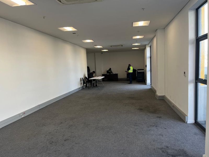 A spacious, open-plan office area featuring recessed ceiling lighting, ducted air conditioning, and large windows providing natural light.