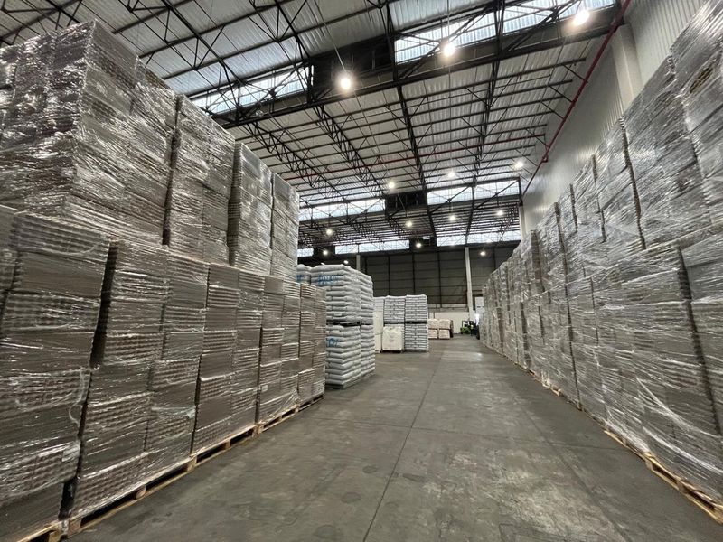 Spacious industrial warehouse featuring high ceilings with exposed steel trusses, high-bay lighting, fire sprinkler systems, and durable concrete flooring.
