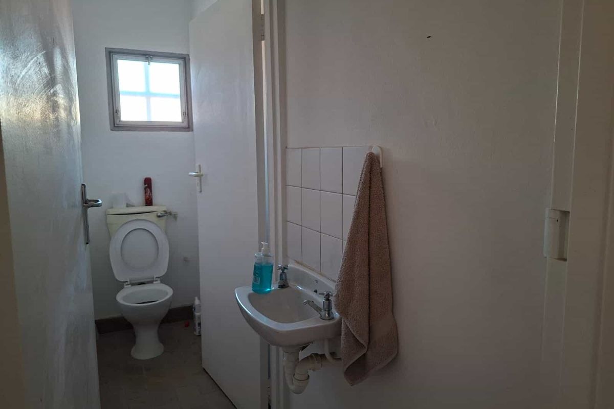 A compact industrial-style bathroom featuring a wall-mounted basin with tiled splashback and a standard toilet.
