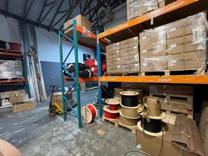 Industrial warehouse storage area featuring heavy-duty steel racking systems, exposed roof trusses, and durable concrete flooring, suitable for bulk inventory management.