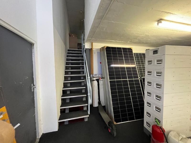 Utility area featuring a staircase and industrial lighting, suitable for storage or access within an industrial property.
