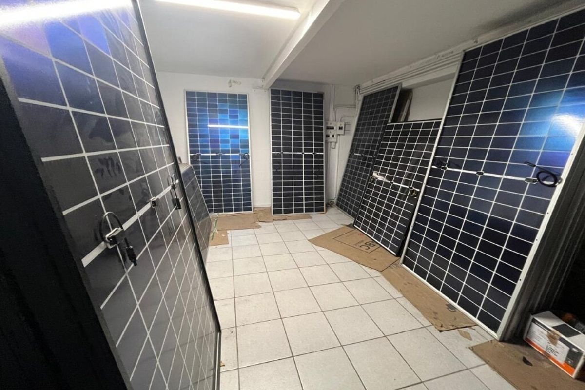 A functional utility space featuring tiled flooring, overhead fluorescent lighting, and an electrical distribution board, currently used for storage.