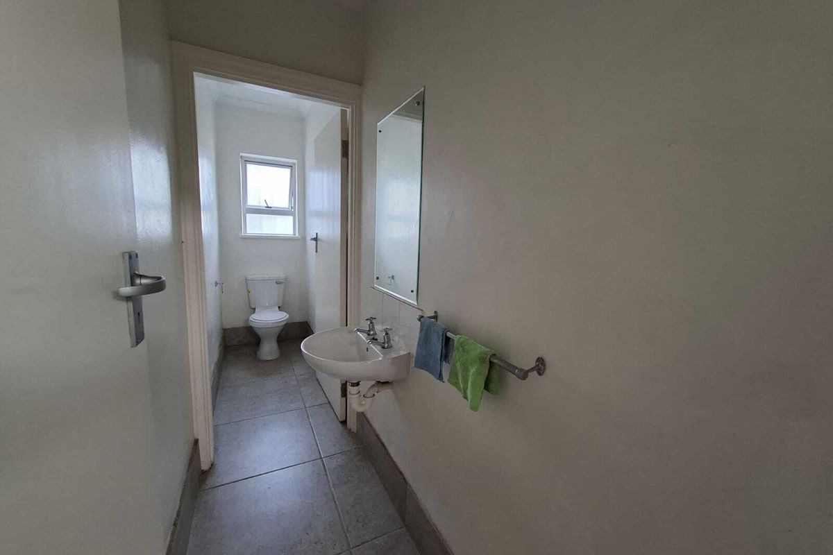 A functional bathroom featuring a wall-mounted basin, toilet, and tiled flooring, providing a clean and practical space.