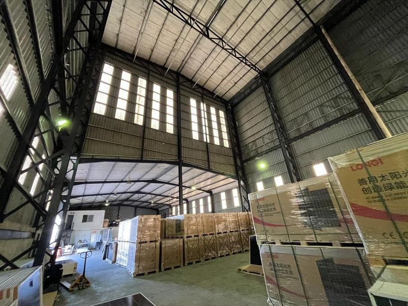 Spacious industrial warehouse featuring high ceilings with exposed steel trusses, concrete flooring, and ample natural light through clerestory windows.
