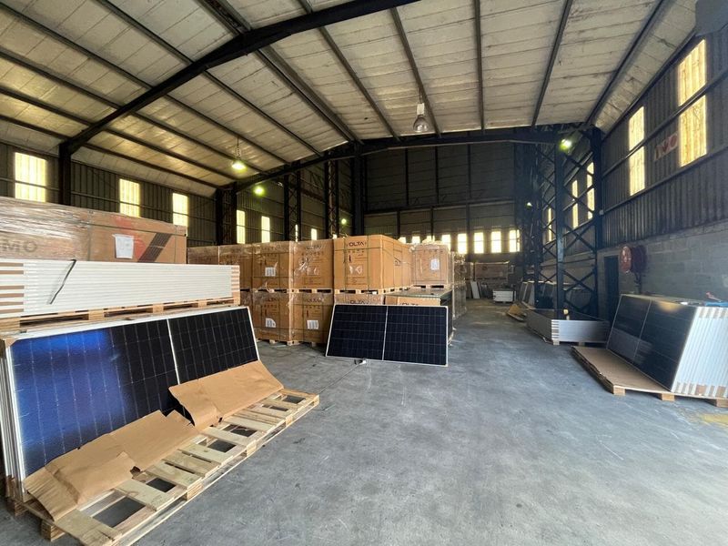 Spacious industrial warehouse featuring a steel portal frame, high ceilings, concrete flooring, and functional industrial lighting, currently utilized for storage.