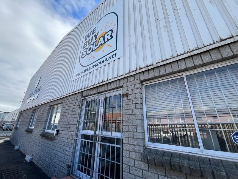 Front elevation of an industrial property featuring corrugated metal cladding, concrete block walls, and secure window and door access points.