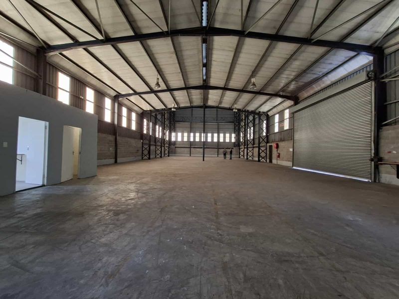 Spacious industrial warehouse featuring a high-clearance steel portal frame, concrete flooring, and a large roller shutter door for efficient access.