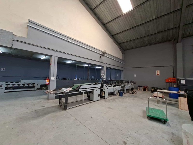Spacious industrial utility area featuring high ceilings with exposed steel trusses, durable concrete flooring, and functional industrial lighting suitable for manufacturing or storage operations.