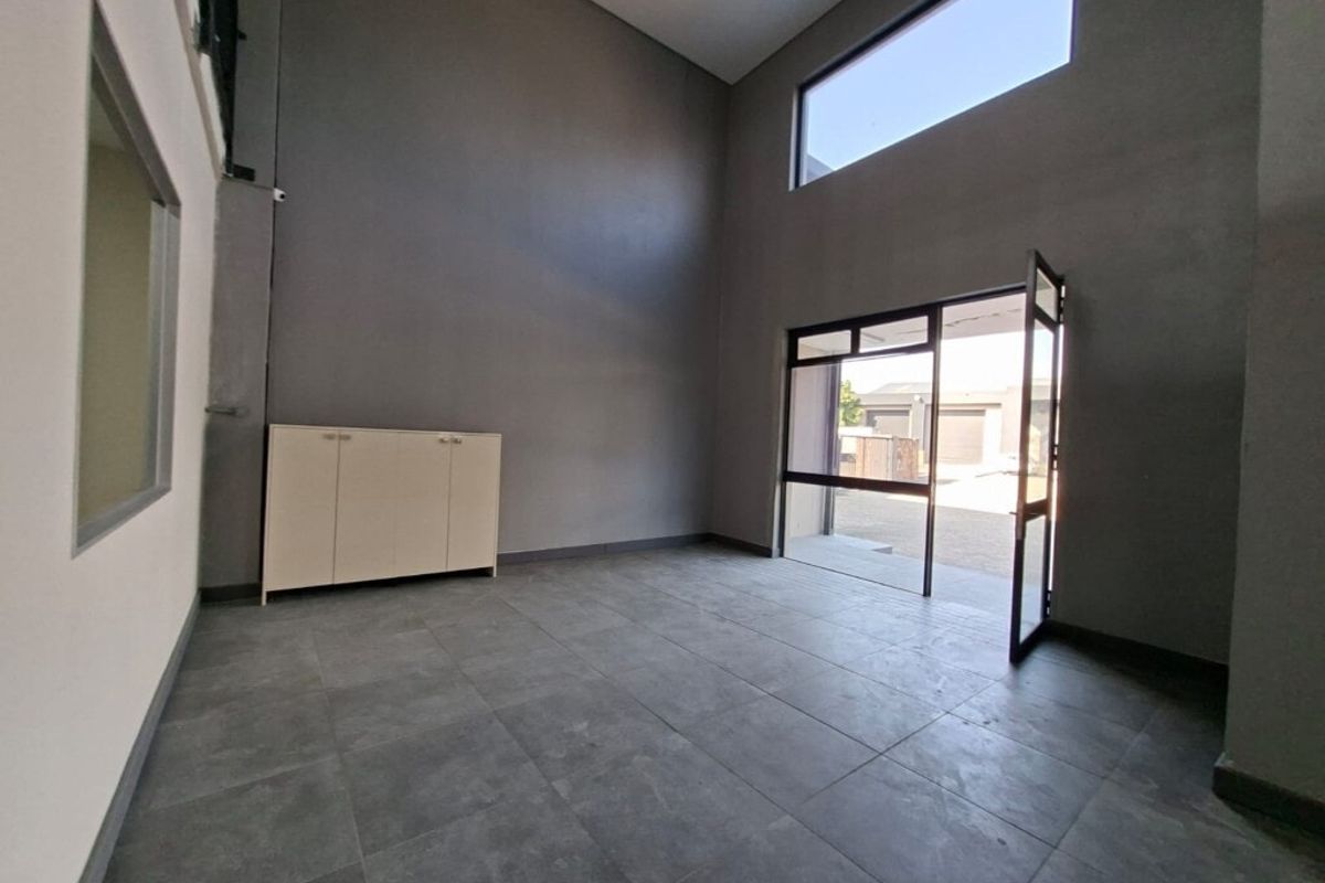 Spacious industrial-style entrance area featuring high ceilings, large windows for natural light, and durable tiled flooring.