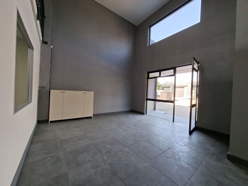 Spacious industrial-style entrance area featuring high ceilings, large windows for natural light, and durable tiled flooring.