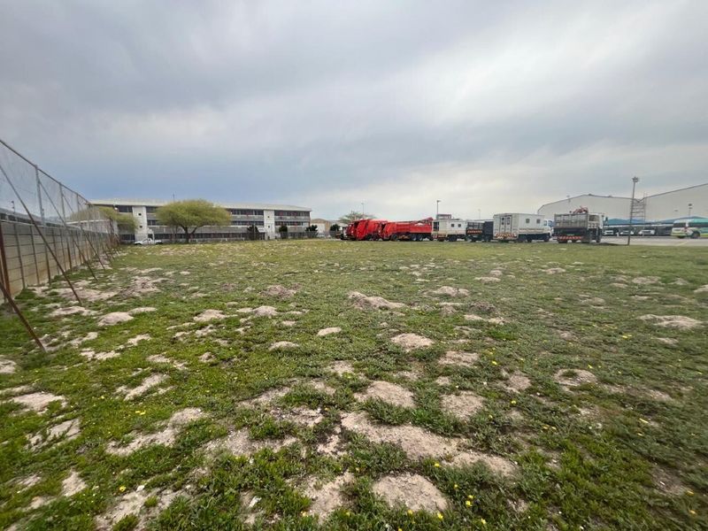 A wide-angle view of an open industrial land plot featuring perimeter chain-link fencing and level ground, suitable for various commercial or industrial development purposes.
