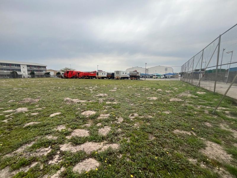 An expansive industrial land plot featuring chain-link perimeter fencing and open, undeveloped ground space suitable for various commercial or industrial storage applications.