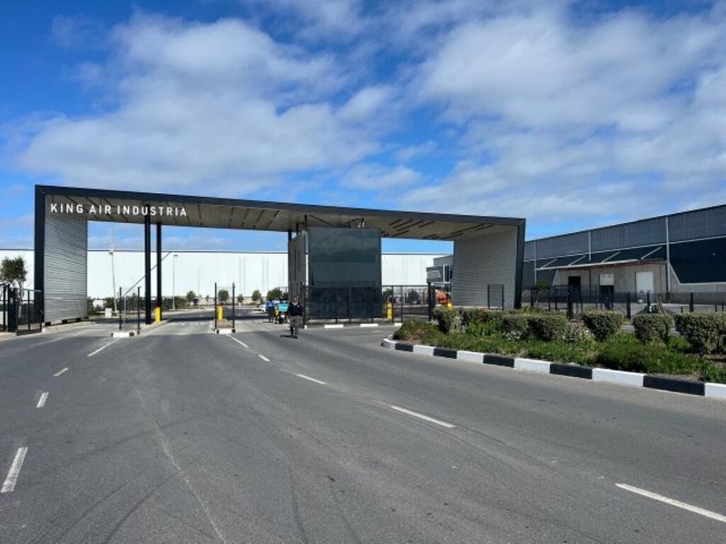 The main entrance and security gatehouse for King Air Industria, featuring modern architectural design, paved access roads, and professional landscaping.