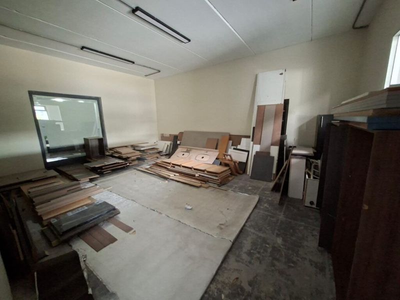 An industrial utility space featuring concrete flooring, fluorescent lighting, and an internal window, currently used for storage.