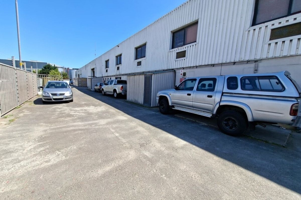 Rear exterior view of an industrial property featuring corrugated metal cladding, concrete driveway, and security fencing.